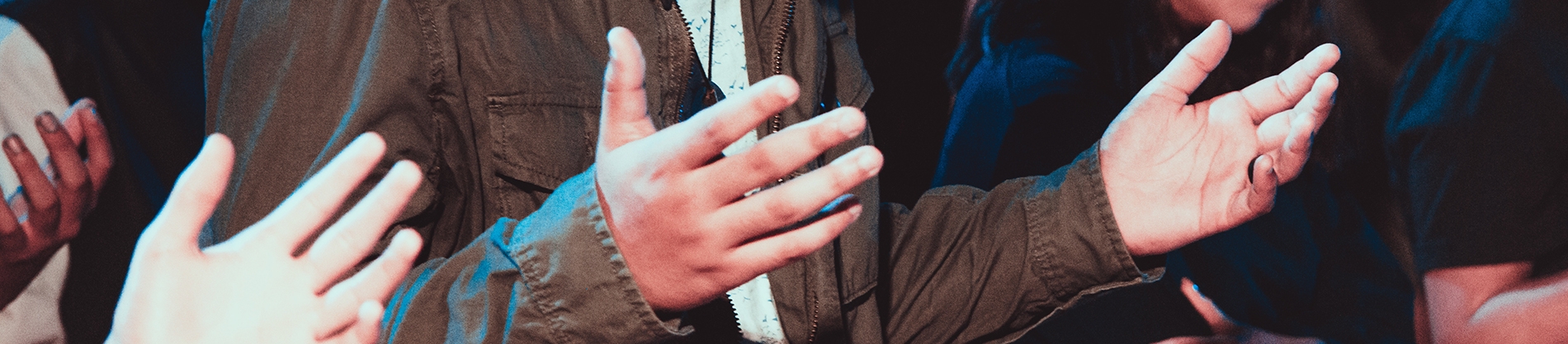 A group of people with their hands open in prayer 