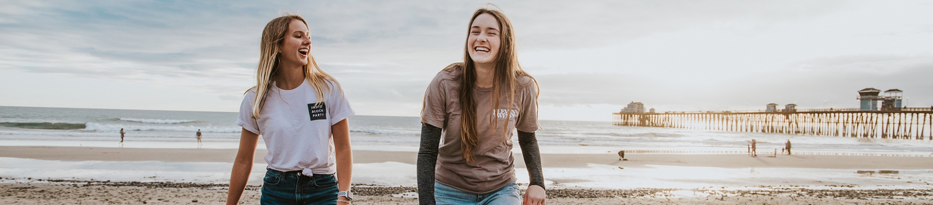 Two women walking and laughing on a beach together